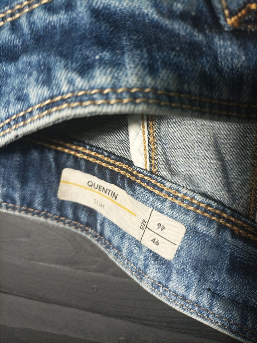 The back of a vintage denim waistcoat featuring a hand-painted illustration of a biker riding a motorbike, in an artistic, worn-in style.