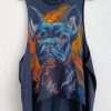 A blue vest featuring a hand-painted portrait of a French Bulldog, rendered with artistic orange and light blue brushstrokes, hanging on a wall.