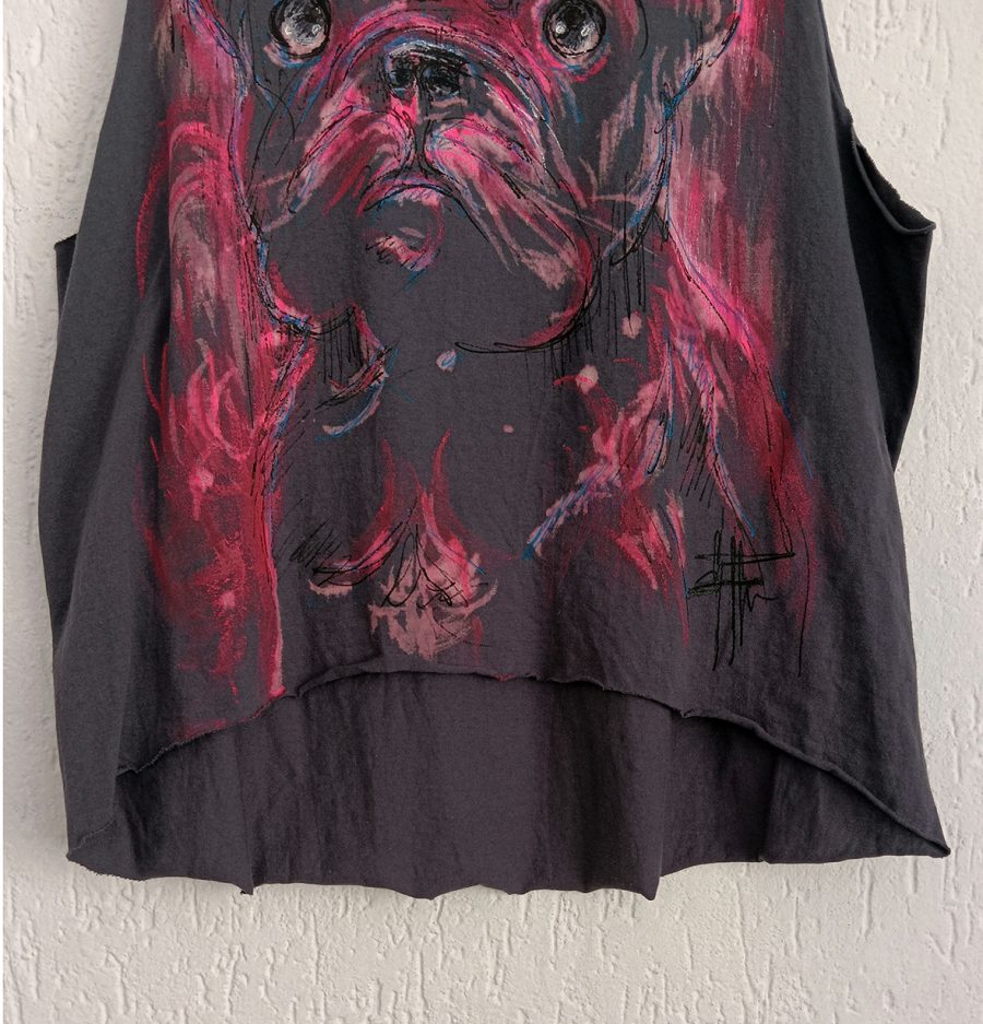 A close-up of the raw-edged hem and the artist’s signature on the handcrafted tank top, featuring fuchsia, red and black paint