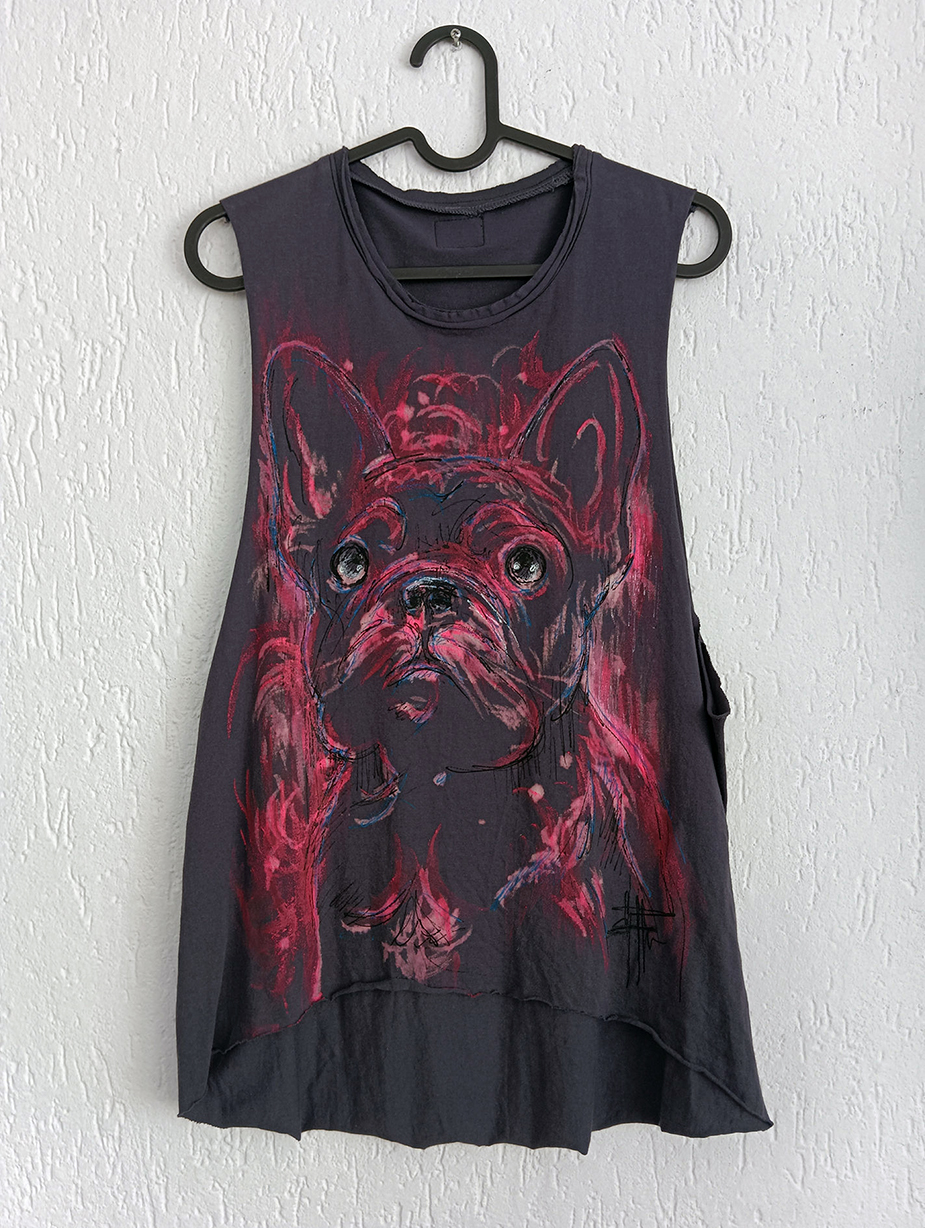 A dark grey vest featuring a hand-painted portrait of a French Bulldog in artistic pink and red brushstrokes, hanging on a wall.