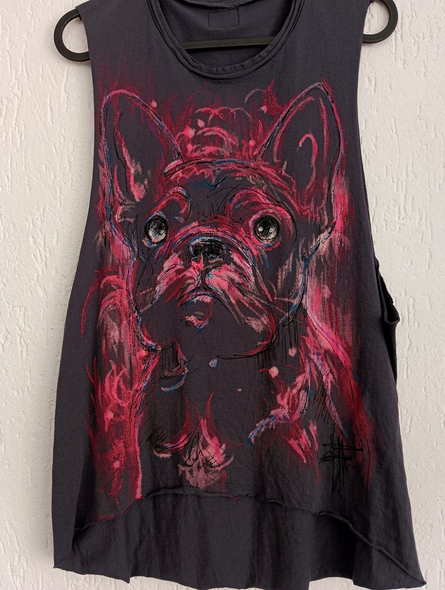 A dark grey vest featuring a hand-painted portrait of a French Bulldog in artistic pink and red brushstrokes, hanging on a wall.