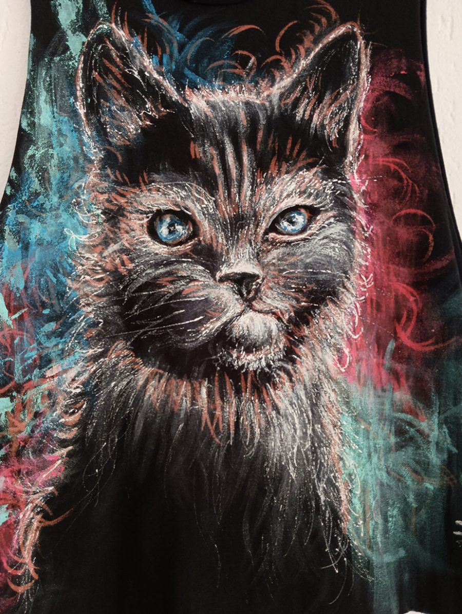 A close-up of a hand-painted picture of a black cat with white fur details and mesmerising ice-blue eyes.